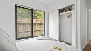 A bedroom with a large window, a wardrobe, and a bed with a 'stay' towel. - StayAU Modern 4BRM TH Bayswater (Bayswater North)