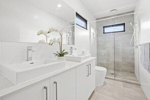 A modern bathroom with two sinks, a glass-enclosed shower, and a potted orchid. - StayAU Modern 4BRM TH Bayswater (Bayswater North)