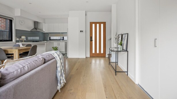 A modern living room with a sofa, a dining table, and a kitchen in the background. - StayAU Modern 4BRM TH Bayswater (Bayswater North)