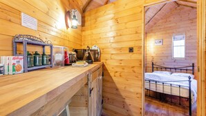A wooden cabin with a kitchenette, a bed, and a window.