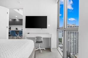 Une chambre d’hôtel avec un lit, un bureau avec une télévision, une chaise et une vue sur le paysage urbain.