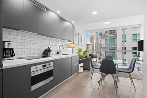 A modern kitchen with a central island, built-in appliances, and a dining area with a glass table and chairs.