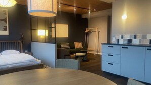 Una habitación de hotel moderna con cama, mesa de comedor, sofá y kitchenette.