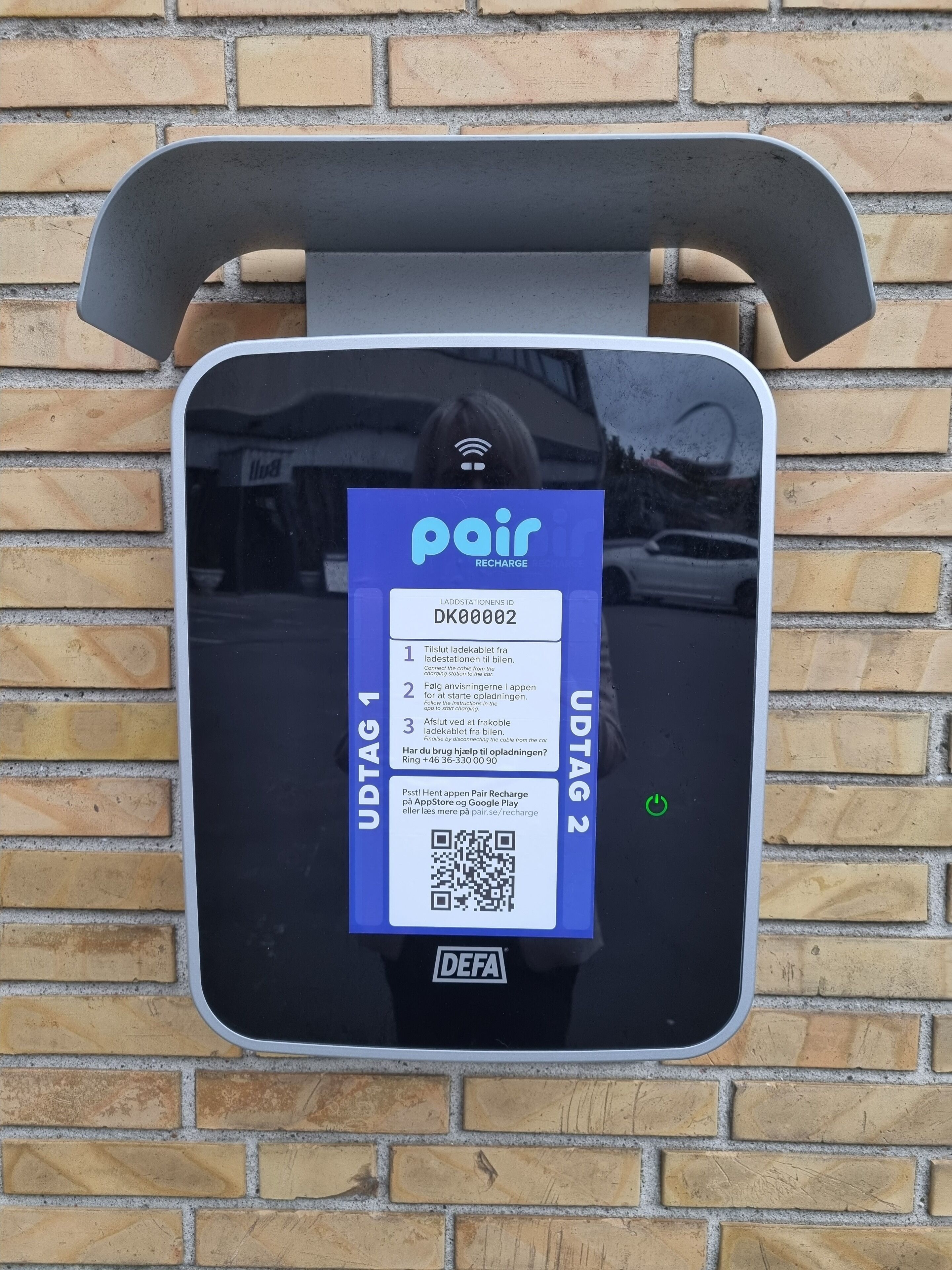 Una estación de carga pública con un letrero azul e instrucciones de uso.