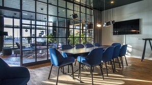 Una sala de conferencias moderna con una mesa grande, sillas azules y ventanas amplias con vistas al exterior.
