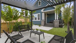 Un patio al aire libre con pérgola, asientos y una pequeña mesa con velas.