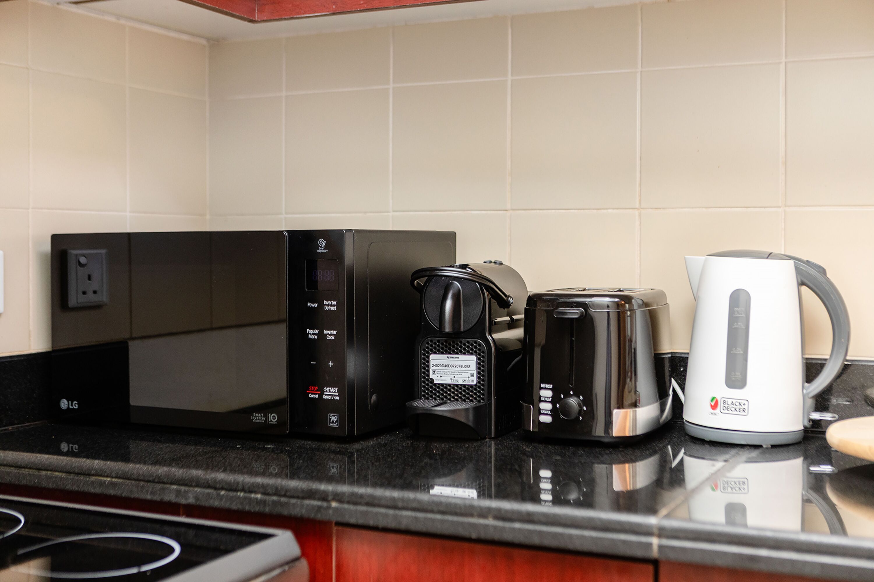 A kitchen with a microwave, coffee maker, and kettle on the counter.