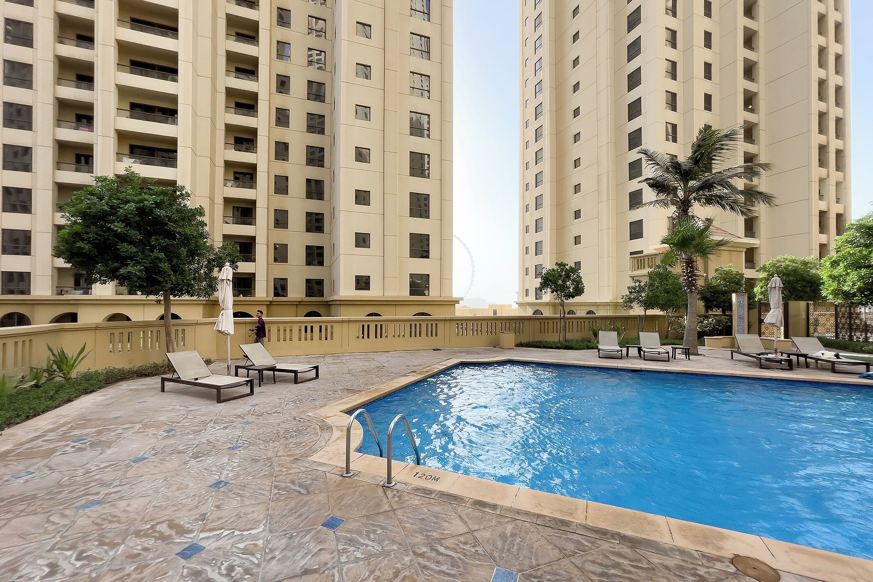 A swimming pool surrounded by lounge chairs and a tall building in the background.