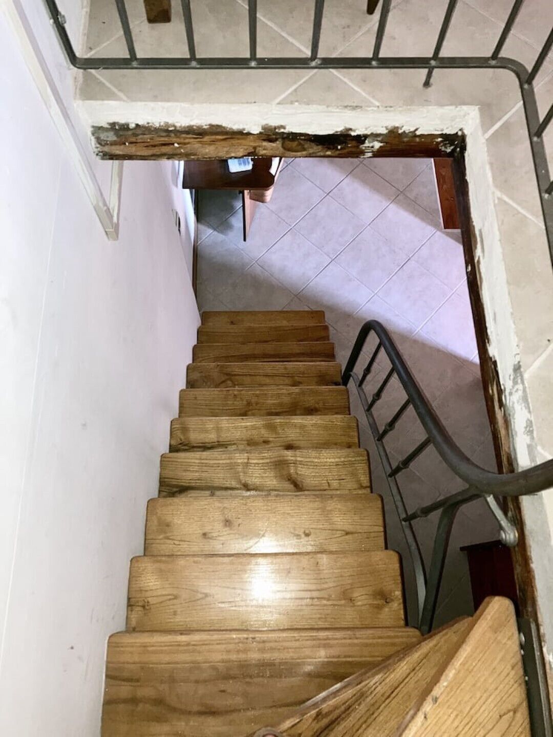 Una escalera de madera con barandillas de metal que da a un suelo de baldosas.