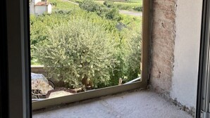 Ein Zimmer mit großem Fenster mit Blick auf einen Weinberg und eine entfernte Hügelkette.
