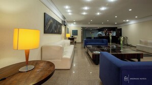 A modern hotel lobby with a sofa, a coffee table, and a lamp. - Rede Andrade São Francisco (Curitiba)
