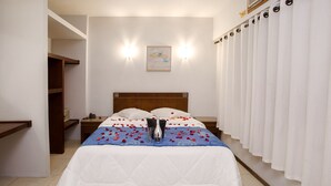 A neatly made bed with a blue and white bedspread, a bedside table with a lamp, and a wall-mounted artwork. - Rede Andrade São Francisco (Curitiba)