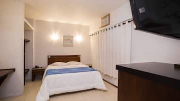 A bedroom with a bed, bedside table, and a TV mounted on the wall.
