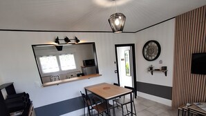 A modern kitchen with a built-in microwave, a wooden dining table, and a black sofa.