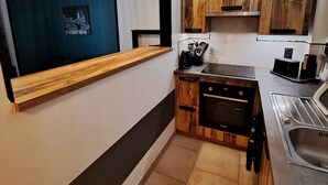 A modern kitchen with wooden cabinets, a built-in oven, and a stainless steel sink.