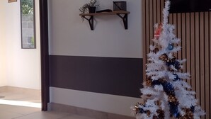 A lobby with a white Christmas tree, a wall clock, a mounted television, and a welcome sign.