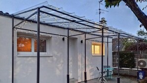 A covered patio area with a pergola structure, a table, and chairs.