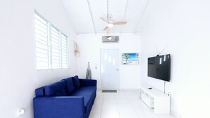 Un salon moderne avec un canapé bleu, un téléviseur à écran plat et un ventilateur de plafond.