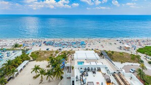 A beach resort with multiple sun loungers, a swimming pool, and a lifeguard tower.