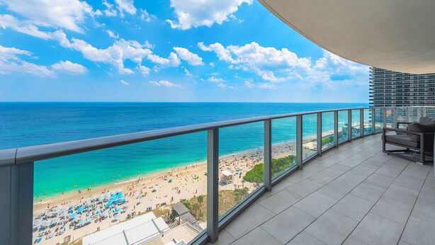 A balcony with a view of a beach and ocean.