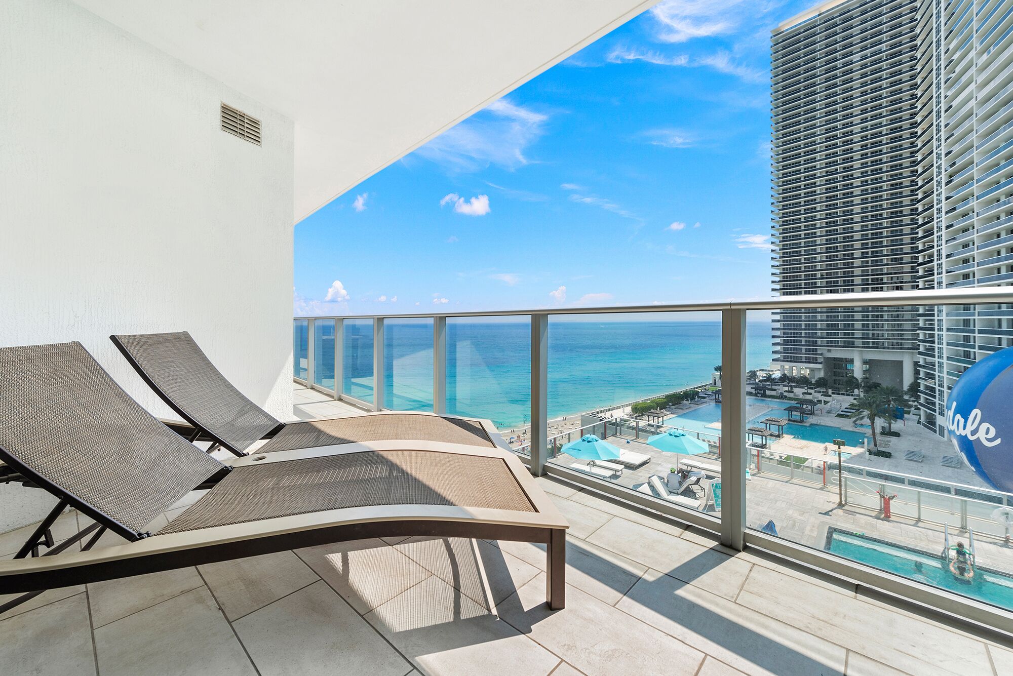 Un balcon avec deux fauteuils de relaxation et une vue sur l’océan et une zone de villégiature.