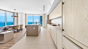A modern kitchen with wooden cabinets, a central island, and a view of the ocean.