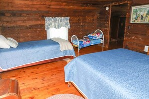 Une cabane avec deux lits, des murs en bois et une porte donnant sur une autre pièce.