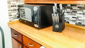 A kitchen with a microwave, a knife block, and wooden cabinets.