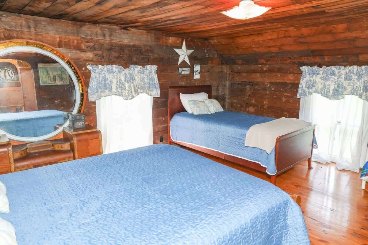 A wooden cabin bedroom with two beds, a round mirror, and a star decoration on the wall.