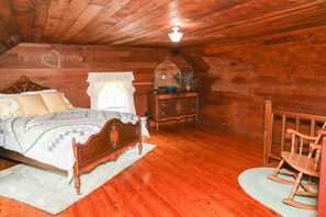 Una habitación de madera con cama, cómoda y mecedora.