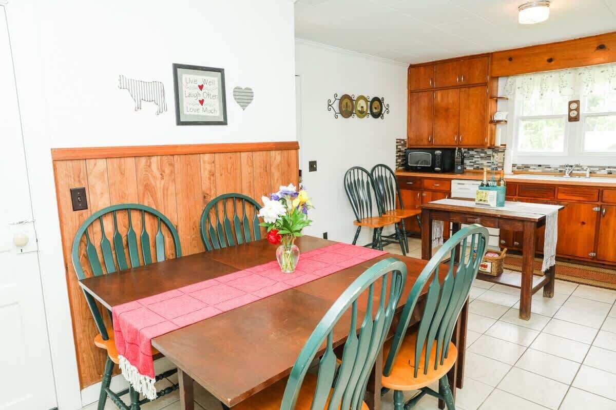 A dining area with a wooden table, green chairs, and a vase with flowers.