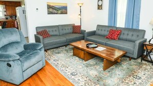 A living room with a grey sofa set, a wooden coffee table, and a patterned rug.