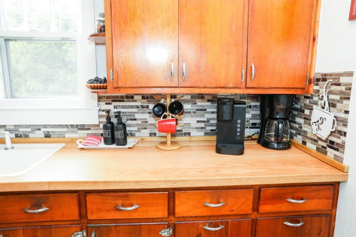 A kitchen with wooden cabinets, a coffee maker, and a tiled backsplash.