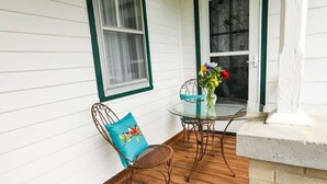 A patio with a glass table and chairs, a vase with flowers, and a brick wall.