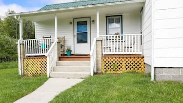 A white house with a porch, a front door, and a small set of steps leading to the entrance.