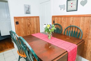 Una mesa de comedor con un florero, paneles de madera en las paredes y una cita enmarcada.