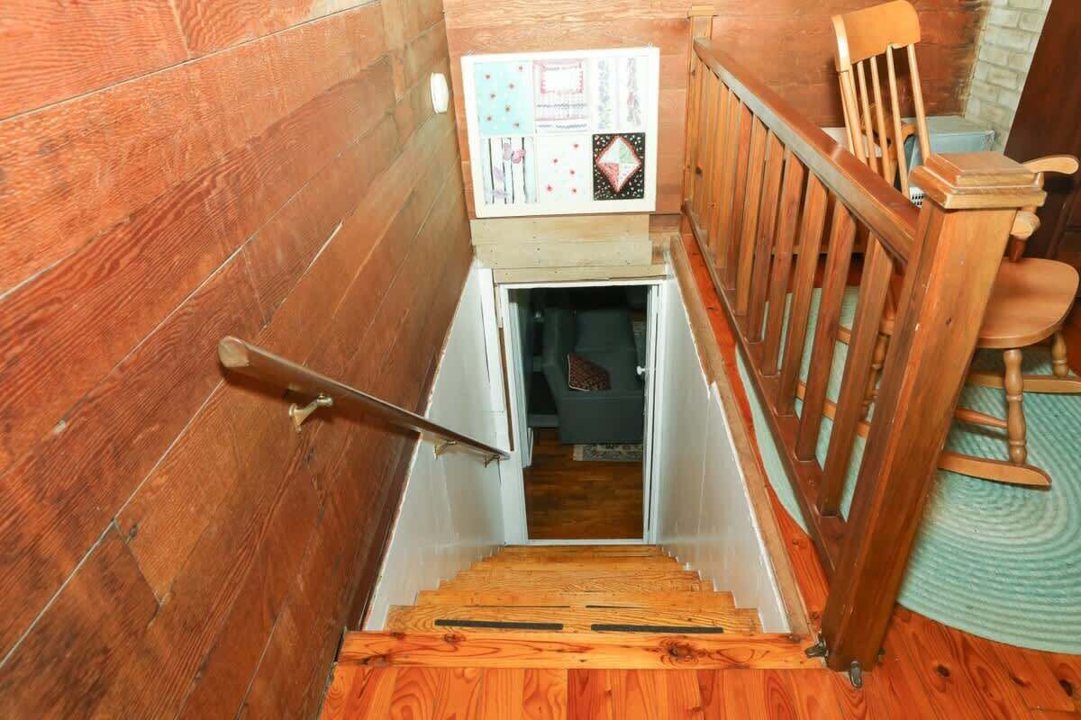 Eine Holzt Treppe mit Handlauf führt zu einem Raum mit einer Tür.
