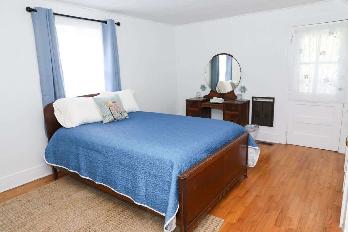 A bedroom with a wooden bed, a dresser, a mirror, and a door.