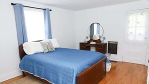 A bedroom with a wooden bed, a dresser, a mirror, and a door.