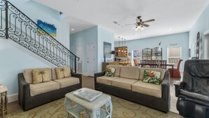 A spacious living room with two sofas, a coffee table, and a dining area with a table and chairs. - Destin Beach House - Flamingo Cove (Miramar Beach)