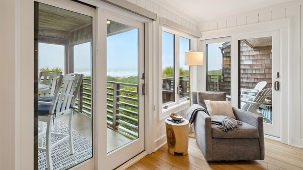 Un balcon avec vue sur l’océan, un coin salon avec un canapé et des fauteuils, et un plancher en bois.