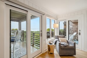 Ein Balkon mit Meerblick, eine Sitzecke mit einer Couch und Sesseln sowie ein Holzboden.