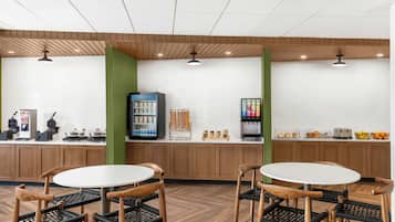 A cafe with wooden furniture, a white tiled wall, and a coffee machine.