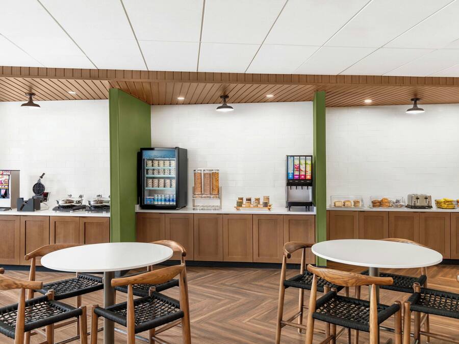 A cafe with wooden furniture, a white tiled wall, and a coffee machine.