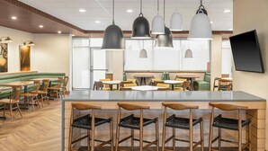 Moderni ravintola, jossa on keskeisellä paikalla sijaitseva baarialue, puulattiat ja riippuvalaisimet.