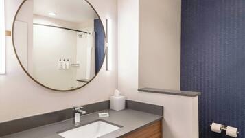 Une salle de bain moderne avec un miroir rond, un lavabo et des toilettes.