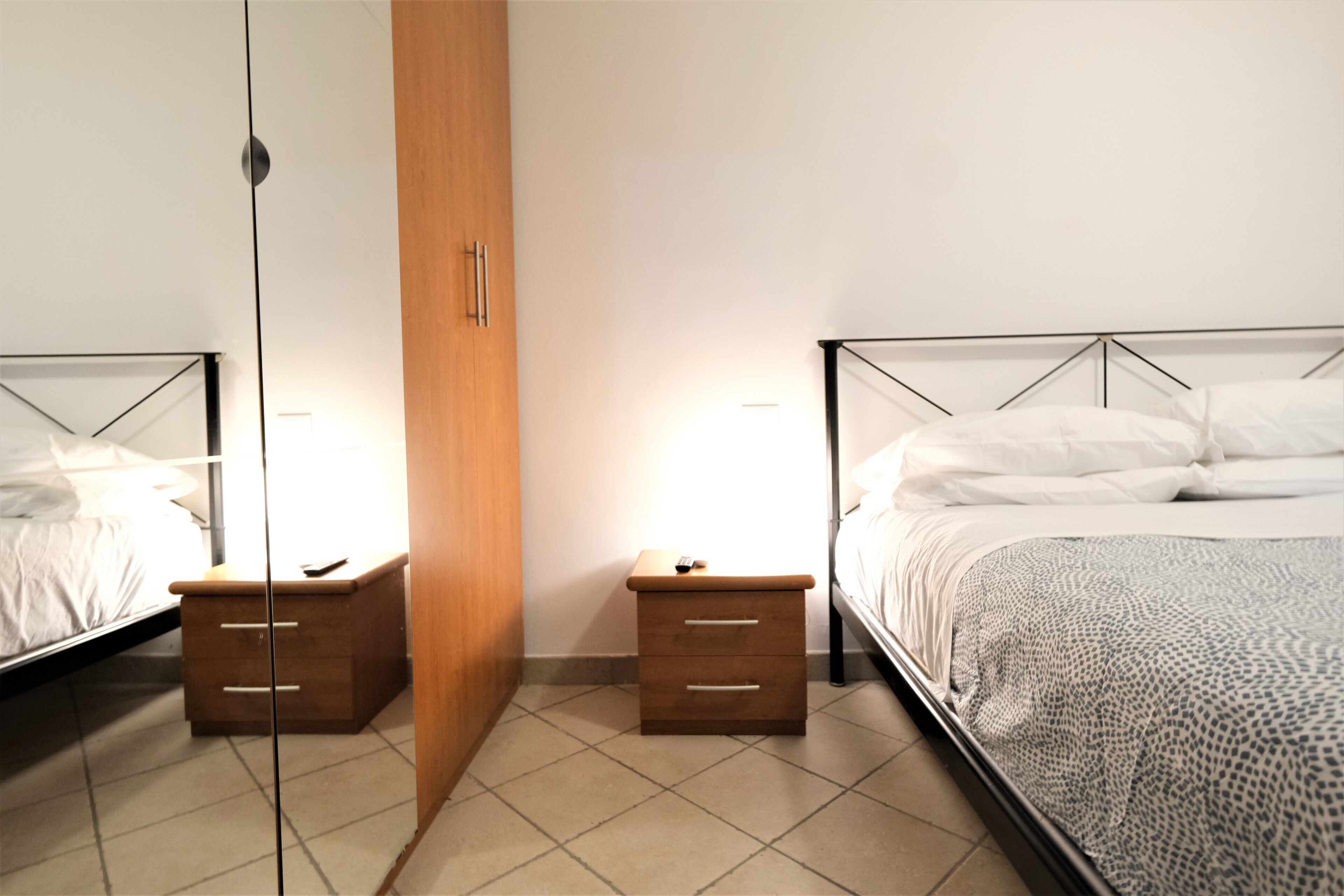 Un dormitorio con dos camas, mesitas de noche de madera y un espejo.