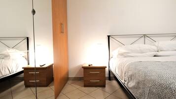 A bedroom with two beds, wooden nightstands, and a mirror.