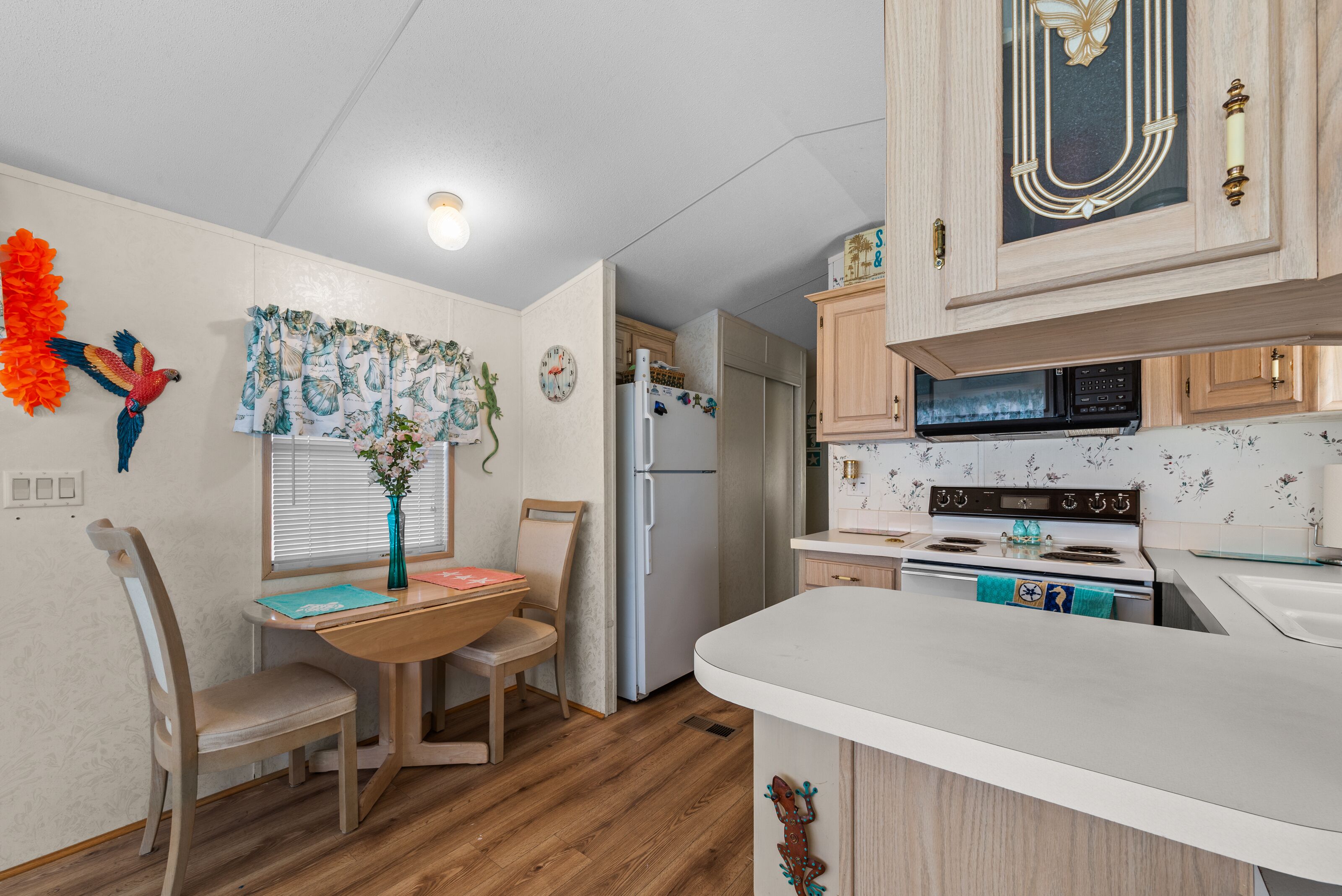 A compact kitchen with wooden cabinets, a refrigerator, a microwave, and a stove.