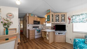 Une cuisine de taille réduite, dotée de meubles en bois, d’un four à micro-ondes, d’un four traditionnel et d’un évier.